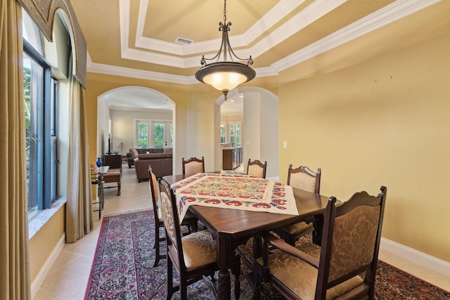 tiled dining space featuring a tray ceiling and ornamental molding