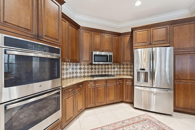 kitchen with crown molding, appliances with stainless steel finishes, light tile patterned floors, and light stone countertops