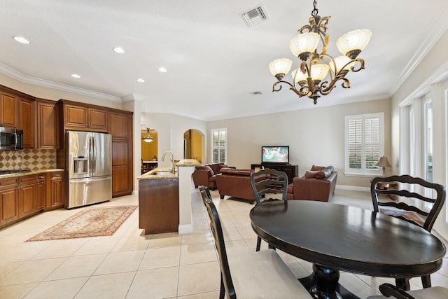 tiled dining room featuring crown molding, a healthy amount of sunlight, sink, and a notable chandelier