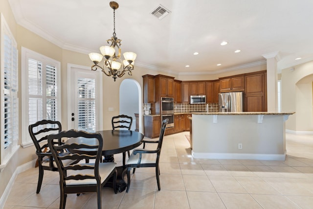 tiled dining room with crown molding and a chandelier