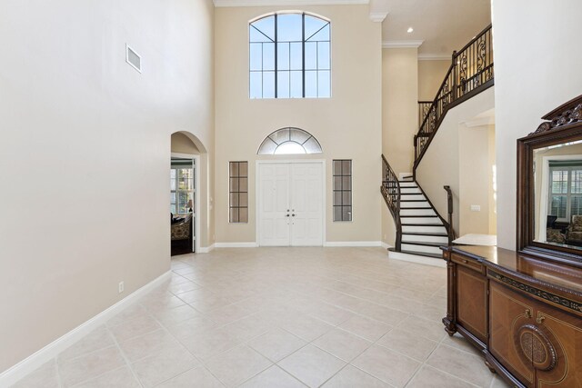 tiled entryway with a towering ceiling and ornamental molding