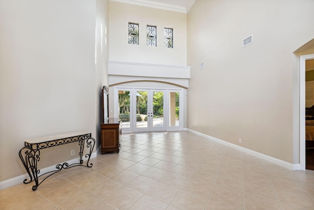 spare room featuring a high ceiling, ornamental molding, light tile patterned floors, and french doors