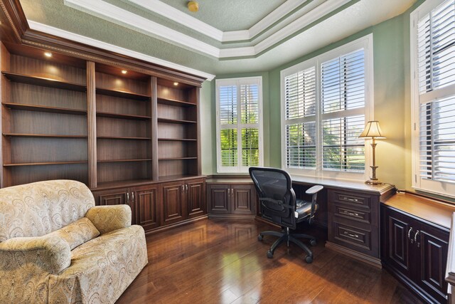 home office with built in desk, ornamental molding, a textured ceiling, dark hardwood / wood-style flooring, and a raised ceiling