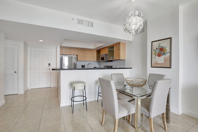 tiled dining room featuring an inviting chandelier and sink