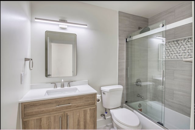 full bathroom featuring combined bath / shower with glass door, vanity, and toilet