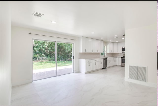 kitchen with decorative backsplash, white cabinetry, sink, and stainless steel appliances