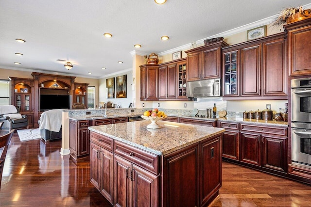 kitchen with crown molding, a kitchen island, appliances with stainless steel finishes, and dark hardwood / wood-style flooring