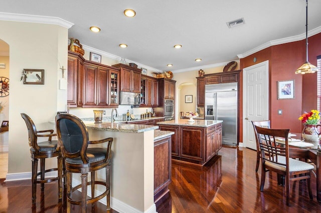 kitchen with decorative light fixtures, stainless steel appliances, dark hardwood / wood-style flooring, kitchen peninsula, and ornamental molding