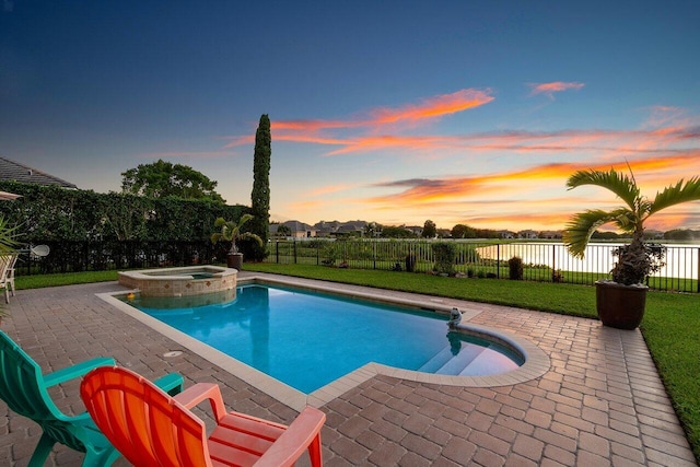 pool at dusk featuring a yard, a patio, and an in ground hot tub