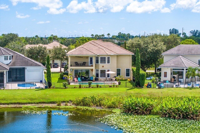 rear view of house with a balcony, a patio area, a lawn, and a water view