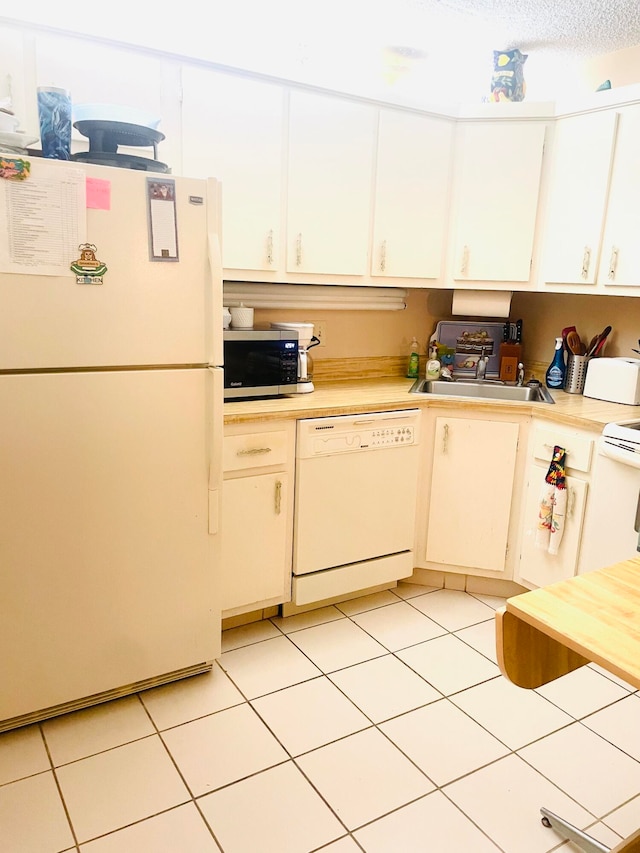 kitchen with white appliances, white cabinets, and light tile patterned flooring