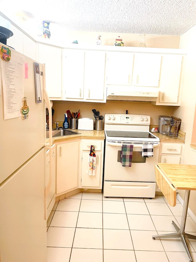 kitchen featuring white appliances, sink, light tile patterned flooring, and a textured ceiling