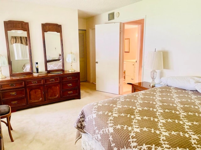 bedroom featuring a closet, light colored carpet, and ensuite bath