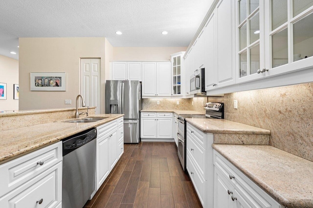 kitchen with dark hardwood / wood-style flooring, light stone counters, stainless steel appliances, sink, and white cabinets