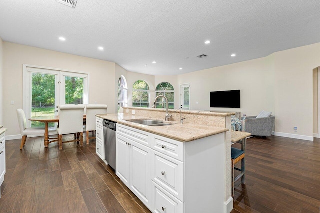 kitchen with a textured ceiling, sink, dishwasher, white cabinetry, and an island with sink