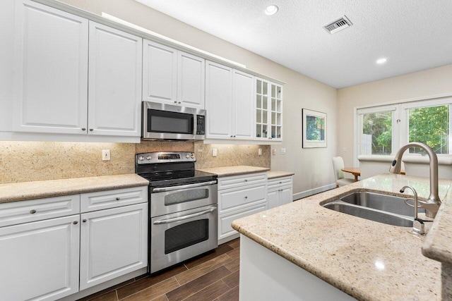 kitchen featuring white cabinetry, sink, light stone countertops, decorative backsplash, and appliances with stainless steel finishes