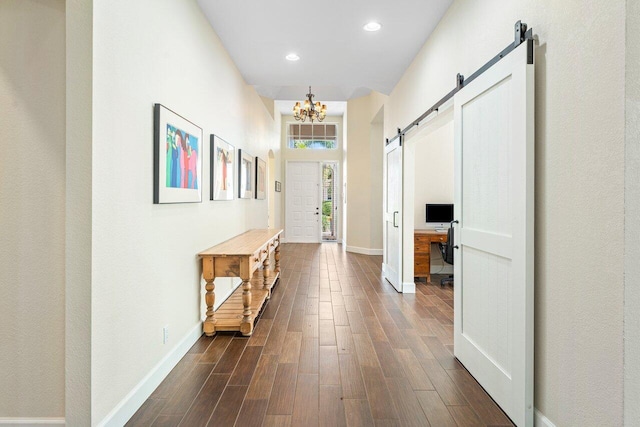 hallway featuring a barn door, a chandelier, and dark hardwood / wood-style floors