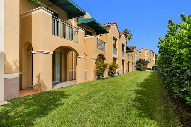 rear view of house with a balcony and a yard