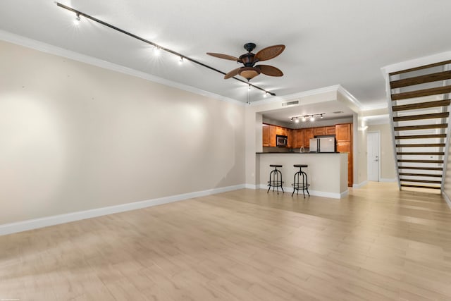 unfurnished living room featuring light hardwood / wood-style flooring, track lighting, and crown molding