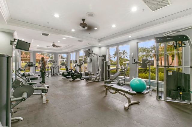 gym featuring ornamental molding, a tray ceiling, and ceiling fan