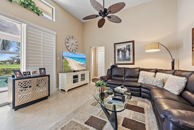 living room featuring a textured ceiling, ceiling fan, high vaulted ceiling, and light tile patterned flooring