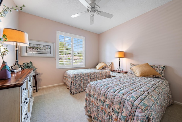 bedroom featuring ceiling fan, light carpet, and a textured ceiling