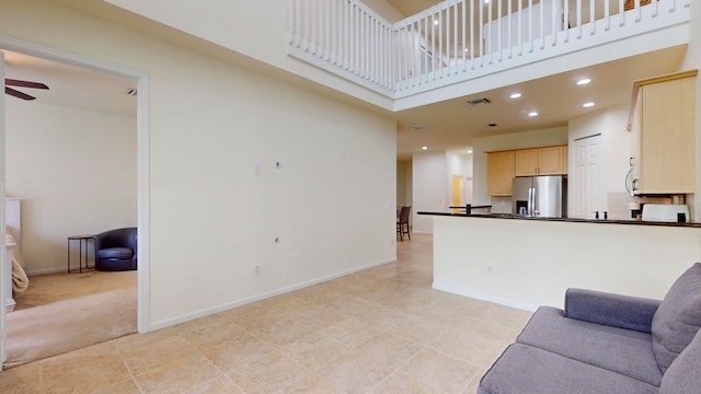 living room with ceiling fan, light tile patterned floors, and a towering ceiling