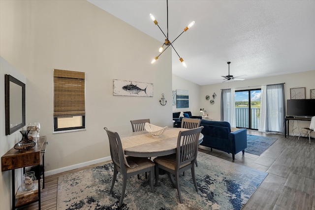 dining area with ceiling fan with notable chandelier, wood-type flooring, a textured ceiling, and high vaulted ceiling