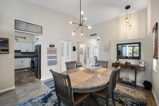 dining area with an inviting chandelier, dark hardwood / wood-style floors, and high vaulted ceiling