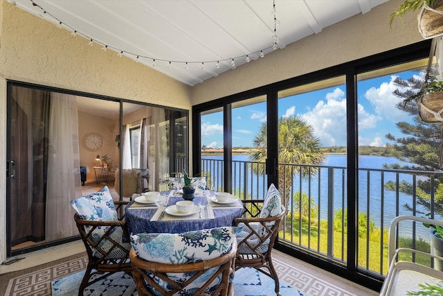 sunroom with a healthy amount of sunlight, a water view, and lofted ceiling