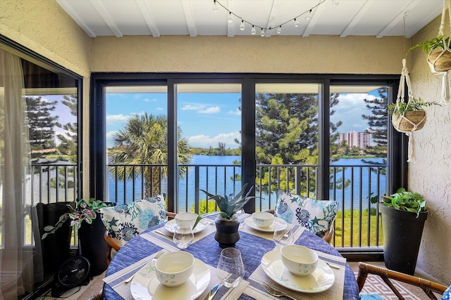 sunroom / solarium with a water view, beamed ceiling, and a wealth of natural light