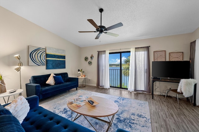 living room featuring vaulted ceiling, ceiling fan, hardwood / wood-style flooring, and a textured ceiling