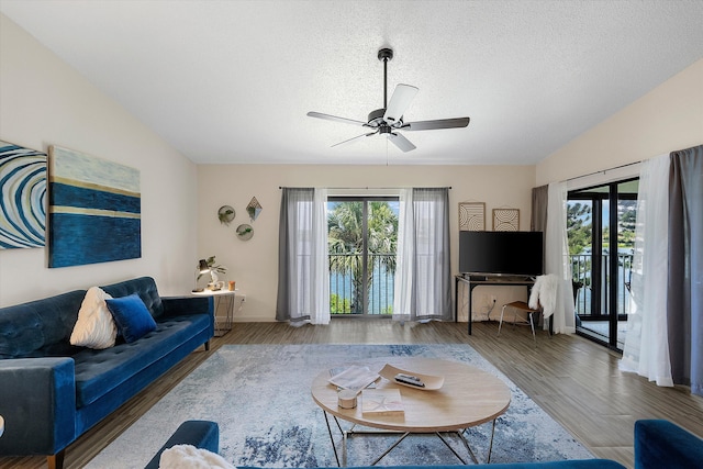 living room featuring a textured ceiling, vaulted ceiling, hardwood / wood-style floors, ceiling fan, and french doors