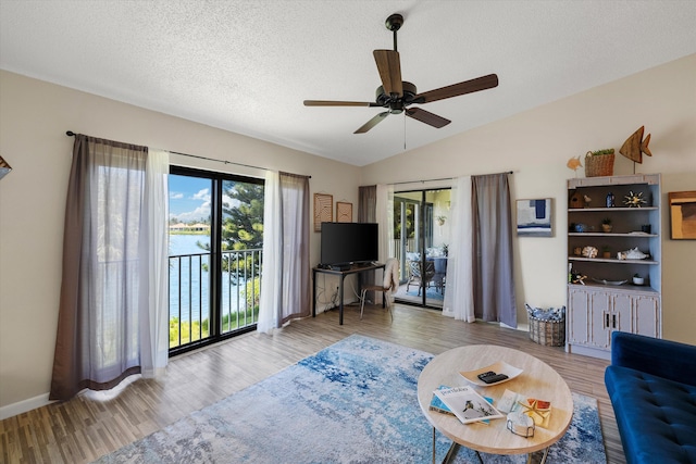 unfurnished living room featuring a wealth of natural light, vaulted ceiling, ceiling fan, and light wood-type flooring