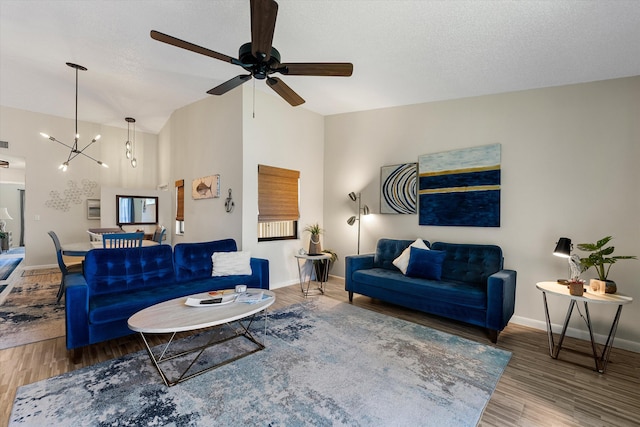 living room with a textured ceiling, ceiling fan with notable chandelier, hardwood / wood-style floors, and high vaulted ceiling