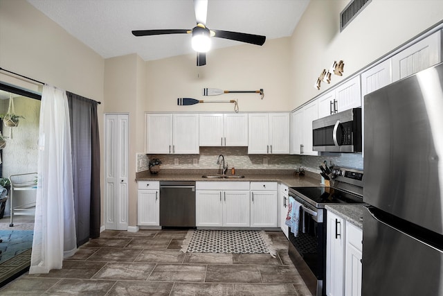 kitchen with ceiling fan, white cabinets, sink, stainless steel appliances, and decorative backsplash