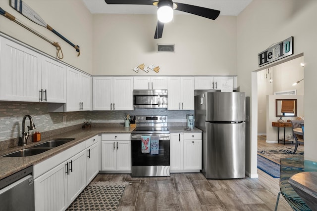 kitchen with hardwood / wood-style flooring, sink, white cabinets, stainless steel appliances, and ceiling fan