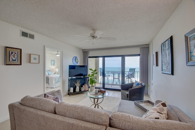 living room with ceiling fan, light tile patterned floors, and a textured ceiling