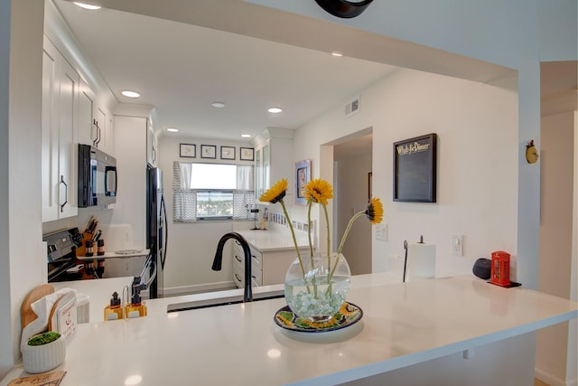 kitchen featuring appliances with stainless steel finishes, kitchen peninsula, white cabinetry, and sink