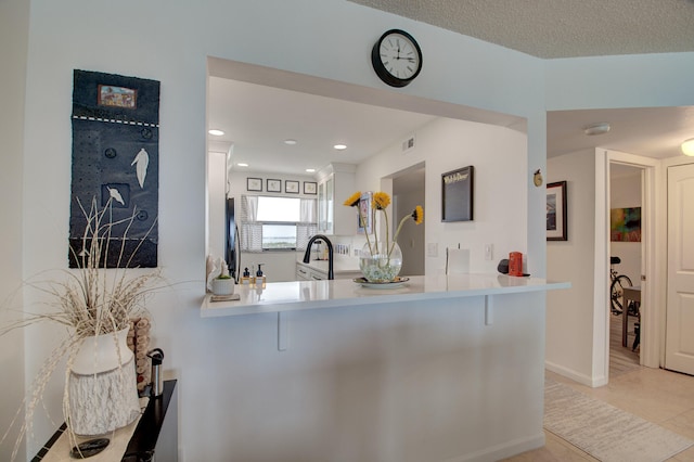 kitchen featuring a kitchen breakfast bar, kitchen peninsula, light tile patterned flooring, and sink