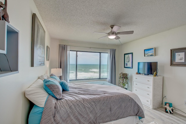 bedroom featuring a textured ceiling, ceiling fan, and light hardwood / wood-style flooring