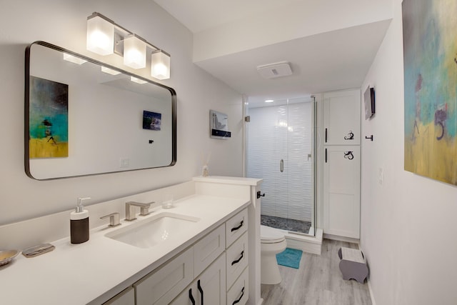 bathroom with hardwood / wood-style floors, walk in shower, vanity, and toilet