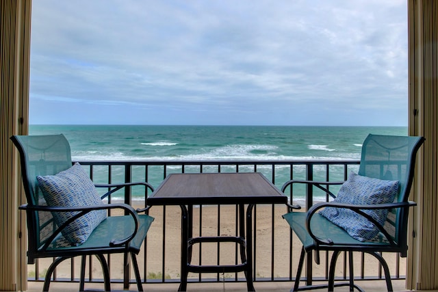 balcony with a water view and a view of the beach