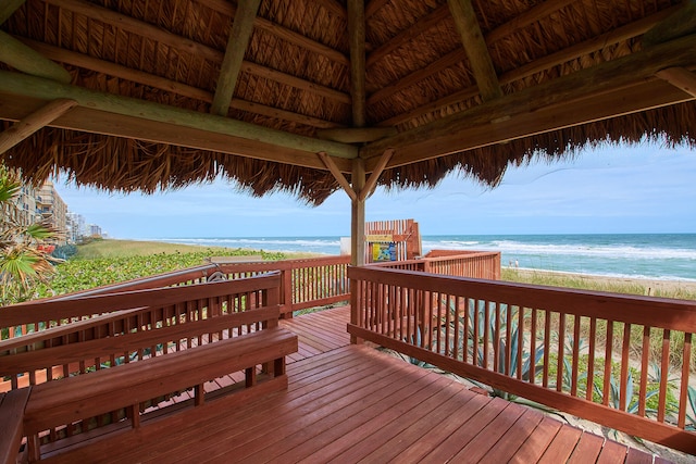 wooden deck featuring a water view and a beach view