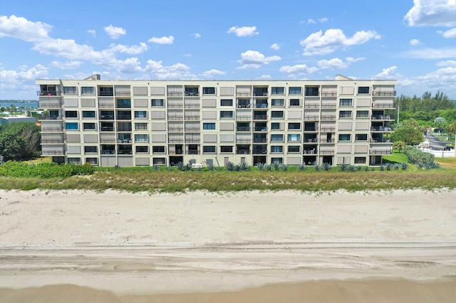 view of property with a water view and a beach view