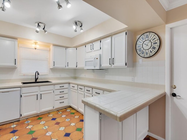 kitchen featuring kitchen peninsula, sink, white appliances, white cabinetry, and tile counters