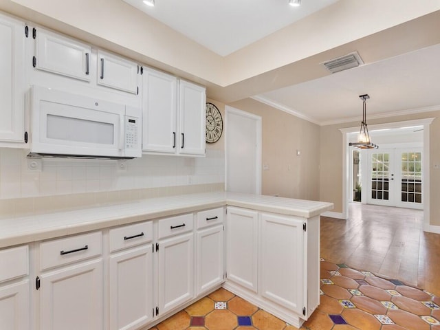 kitchen with white cabinets, kitchen peninsula, pendant lighting, light wood-type flooring, and french doors