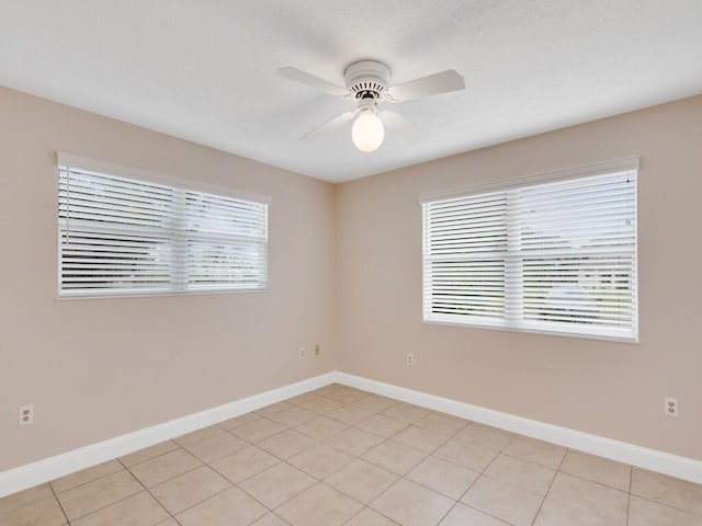 tiled spare room featuring ceiling fan and a healthy amount of sunlight