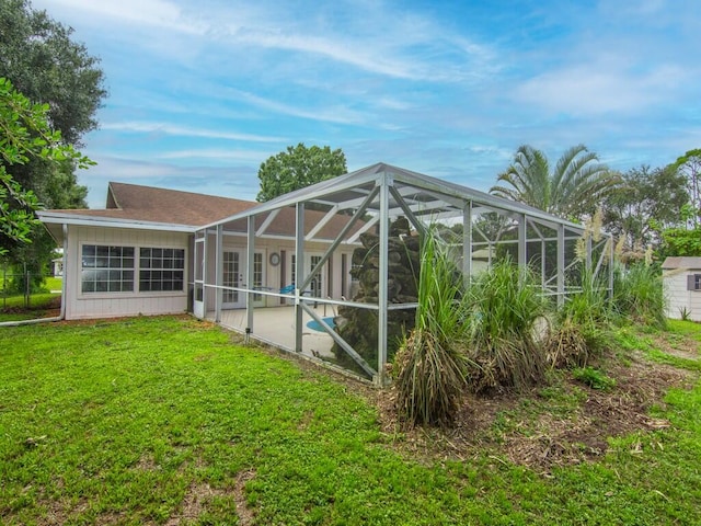 rear view of property featuring a yard and glass enclosure