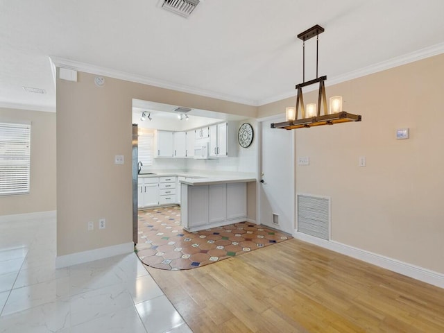 kitchen with pendant lighting, sink, white cabinets, light hardwood / wood-style flooring, and ornamental molding